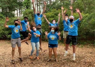 Workers wearing blue union T-shirts jump with their hands up
