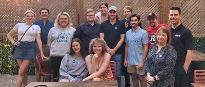 A group of 13 workers smiles 