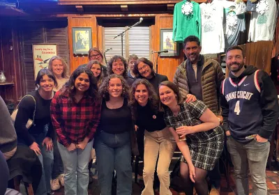 A group of 13 people smile 